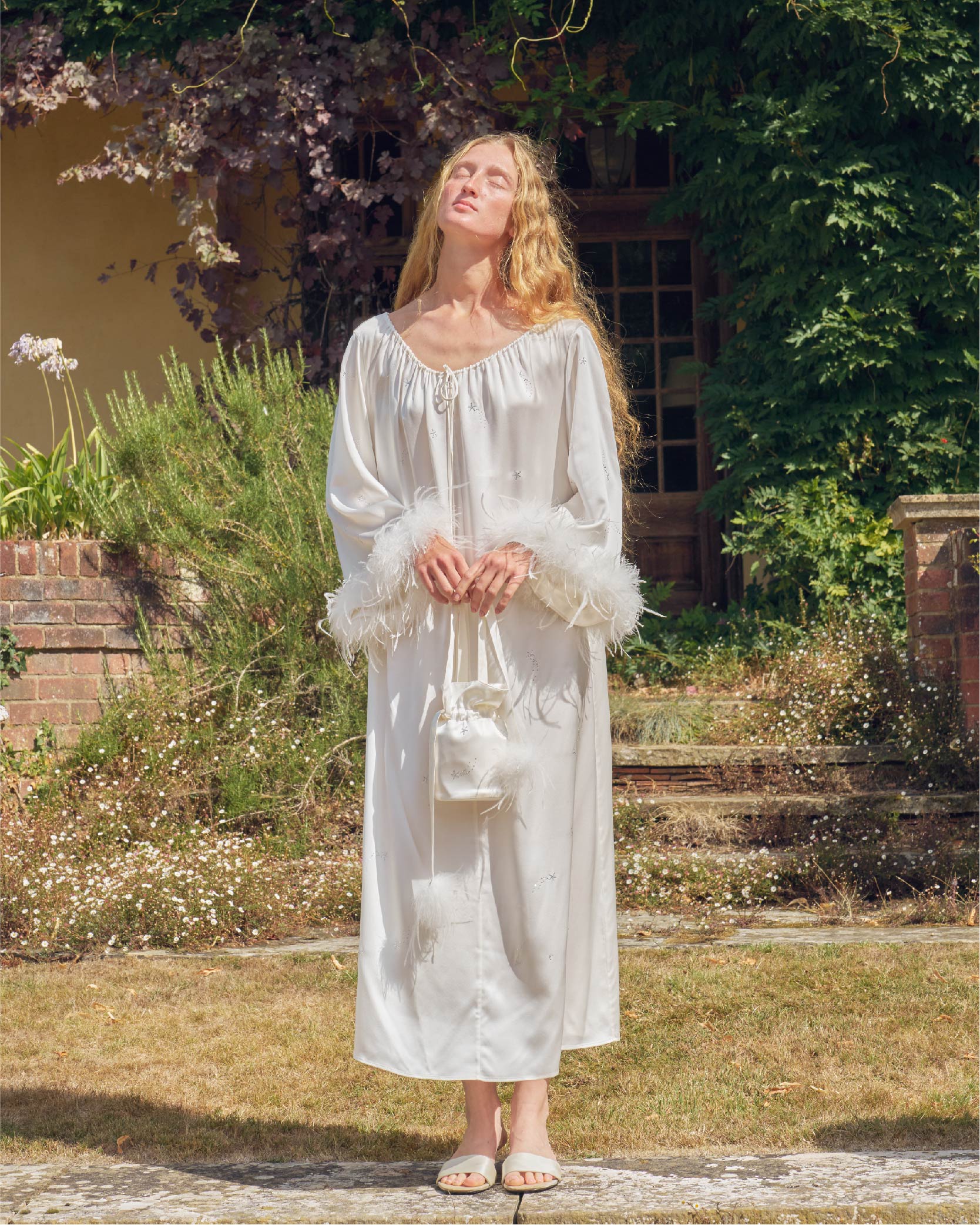 Woman in a white silk dress standing in a garden with a blurred background