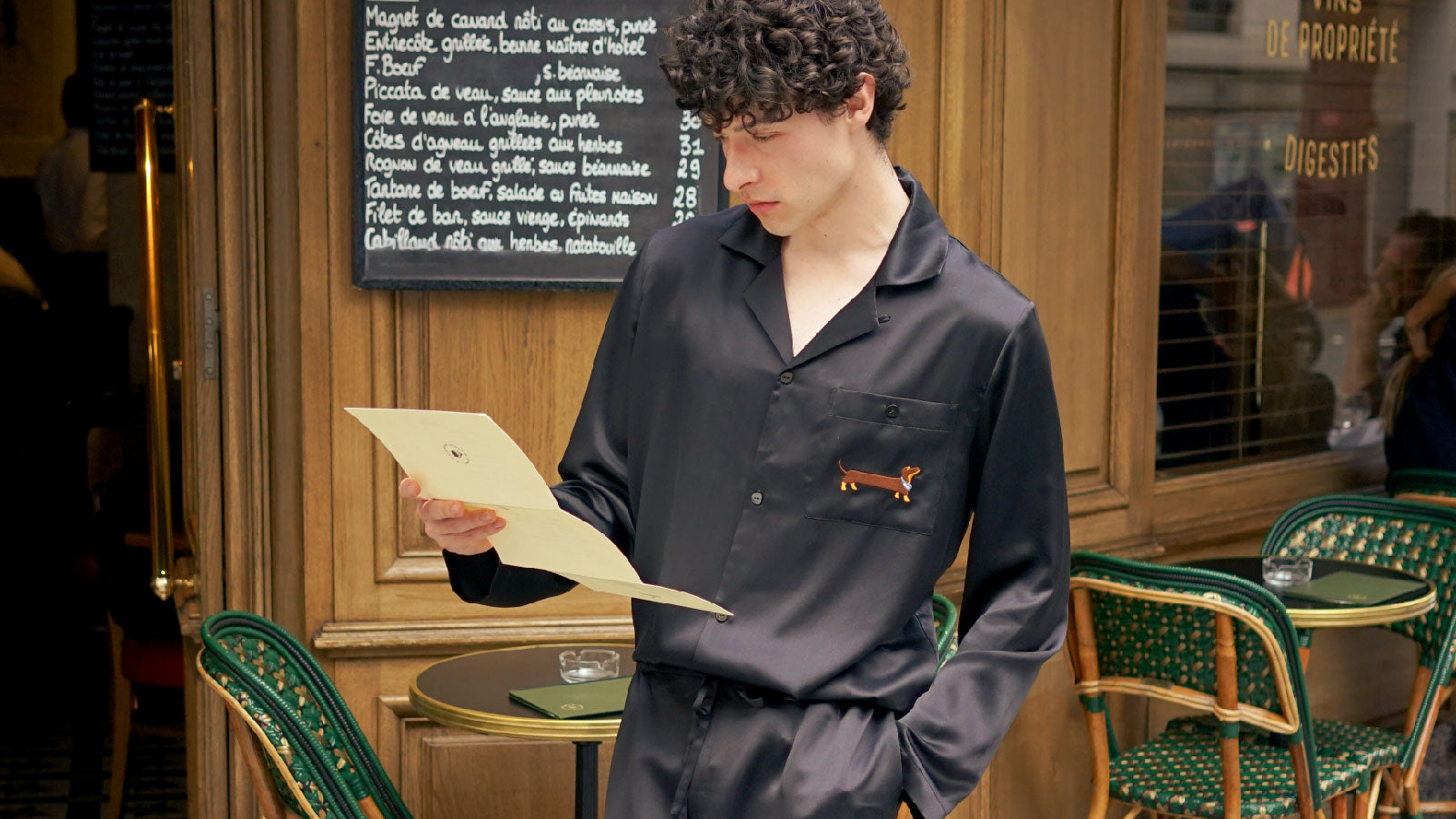 Man wearing black silk pajamas, reading outdoors