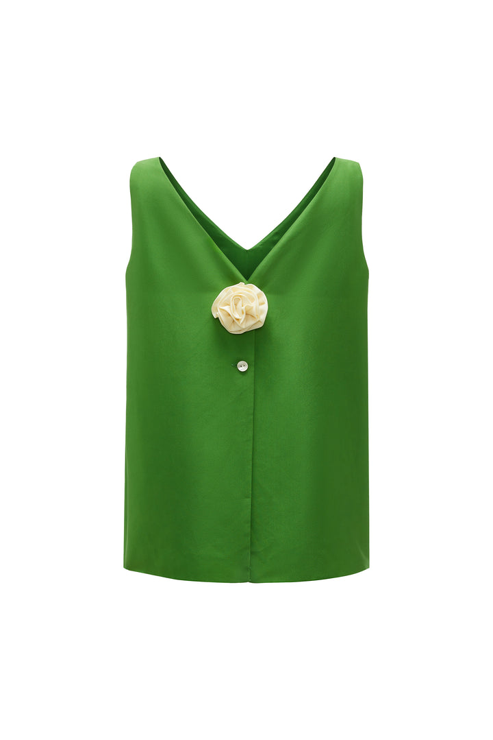 Green sleeveless top with a floral brooch on a white background