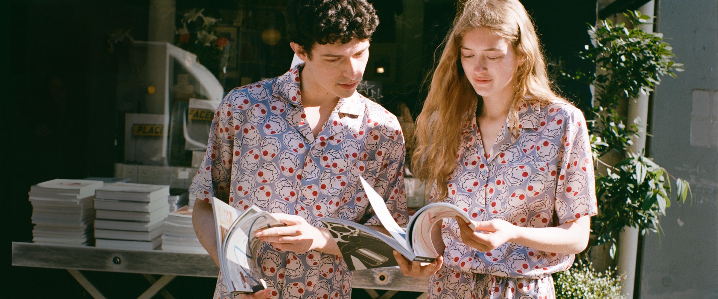 Two people in matching floral outfits looking at a book outdoors.